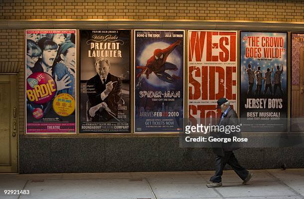 Man walks past a series of Broadway musical billboards outside the Shubert Theatre as seen in this 2009 New York, NY, early morning cityscape photo.