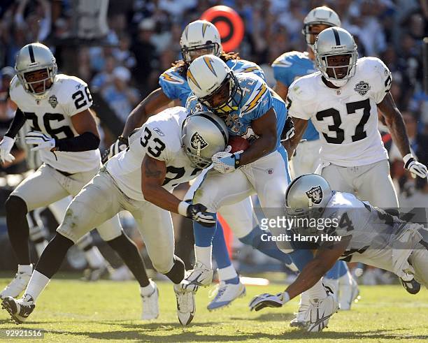 Darren Sproles of the San Diego Chargers gets hit by Tyvon Branch and Michael Huff of the Oakland Raiders during the game at Qualcomm Stadium on...