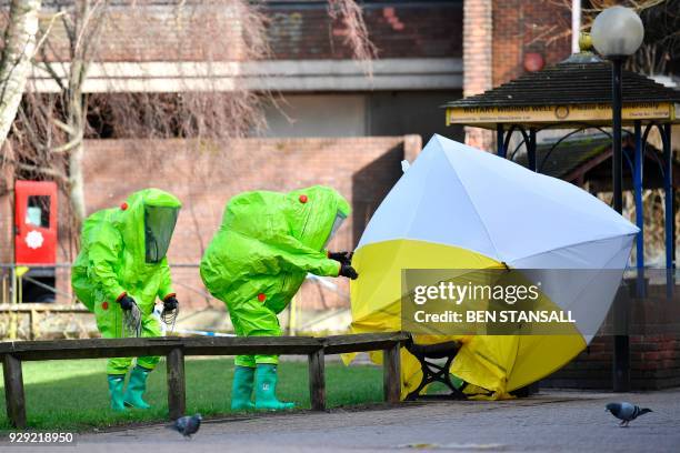 Members of the emergency services in green biohazard encapsulated suits afix the tent over the bench where a man and a woman were found on March 4 in...