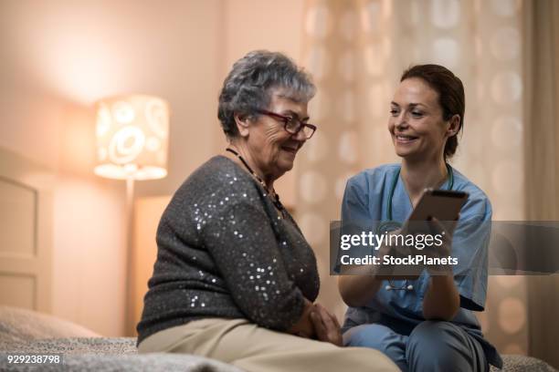 young nurse helping senior women with tablet - heroes 2017 show stock pictures, royalty-free photos & images