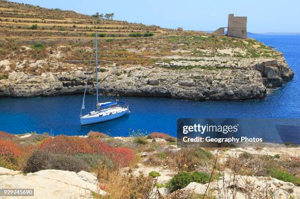 Yacht and watchtower at entrance to Mgarr ix-Xini coastal inlet, island of Gozo, Malta.