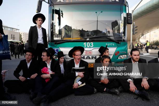 Israeli Ultra-Orthodox Jewish men block a bus while demonstrating against army conscription on March 8, 2018 in Jerusalem.