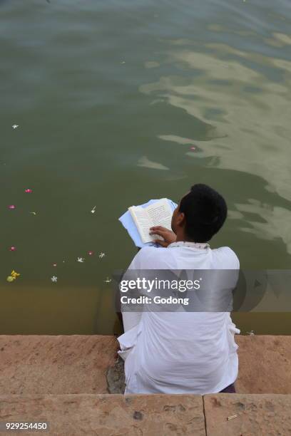 Hindu reading a spiritual book on the steps leading to Goverdan Radha Kund. India.