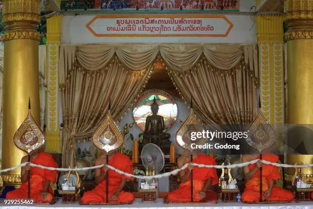 Seated Buddhist monks praying at a buddhist ceremony. Remembrance of the deceased. Wat Ong Teu Mahawihan. Temple of the Heavy Buddha. Vientiane, Laos.