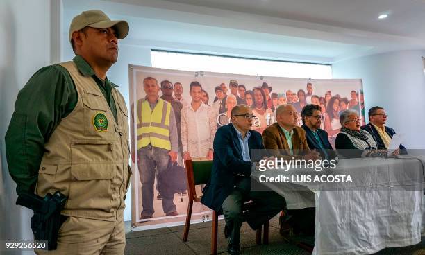 Police officer stands guard as leaders of the Common Alternative Revolutionary Force political party offer a press conference in Bogota on March 8,...