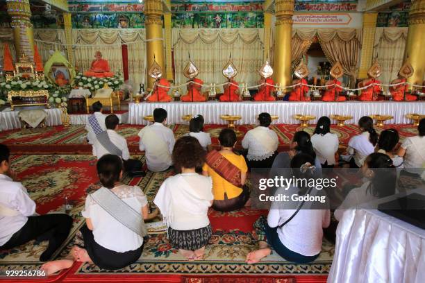 Seated Buddhist monks praying at a buddhist ceremony. Remembrance of the deceased. Wat Ong Teu Mahawihan. Temple of the Heavy Buddha. Vientiane, Laos.