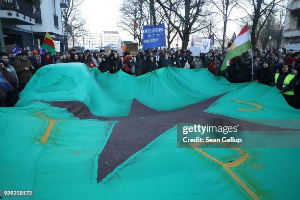 Women hold up a giant flag of the Kurdish YPG militia at the beginning of a march for women's rights at Schlesisches Tor on International Women's Day...