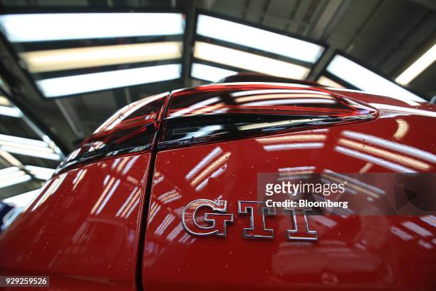Badge sits on a newly assembled Volkswagen AG Golf GTI automobile as it stands in the light tunnel during final quality checks at the VW factory in...