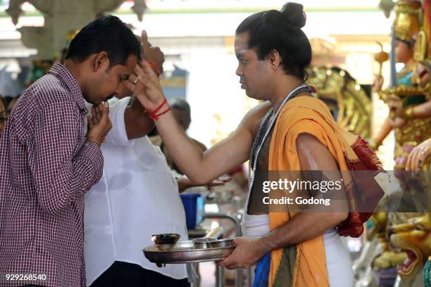 Sri Veeramakaliamman Hindu Temple. Hindu Brahmin priest. Applying tika. Hindu devotees during a morning prayer or puja. Singapore.