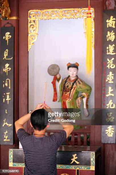 Thian Hock Keng Temple. A Chinese young man praying and offering incense. Buddhist Worshipper. Burning incense sticks. Yue Gong Niang Niang: the moon...