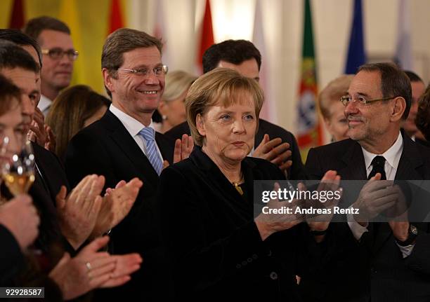 German Chancellor Angela Merkel claps as her Foreign Minister Guido Westerwelle smiles and European Council High Representative Javier Solana looks...