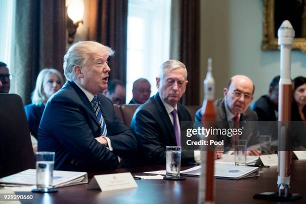 President Donald J. Trump speaks beside US Secretary of Defense Jim Mattis and US Commerce Secretary Wilbur Ross , with rocket models seen on the...