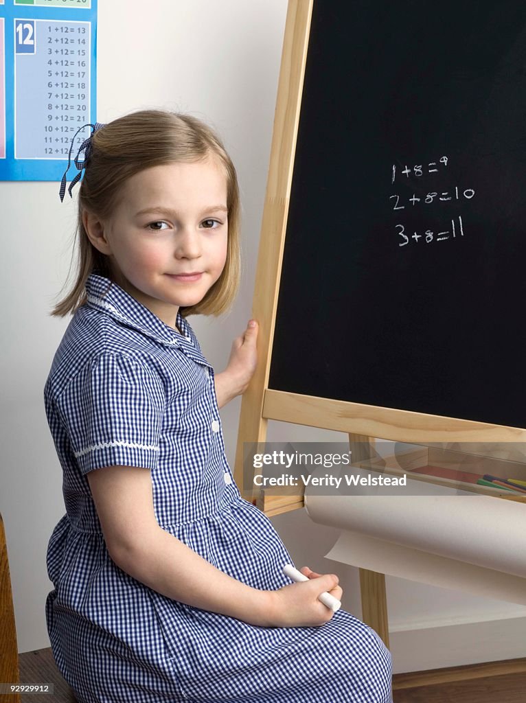 Girl posing by chalkboard in school classroom