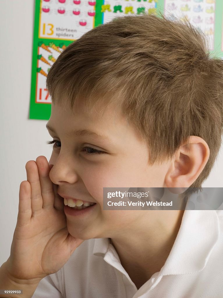 Smiling boy whispering in classroom