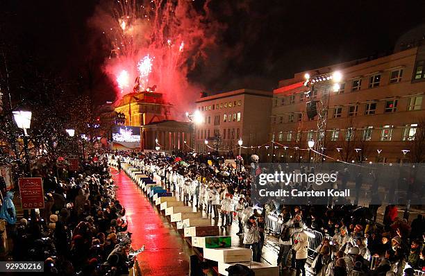 Spectators watch as giant, painted styrofoam dominoes topple along the route of the former Berlin Wall near the Brandenburg Gate on November 9, 2009...