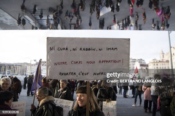 Woman holds a placard reading "Neither priest, nor rabbi, nor imam. Our body belongs to us! To abort is our right." during a demonstration to defend...