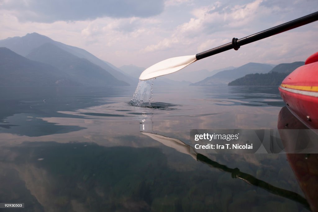 Layak paddle dipping into calm lake
