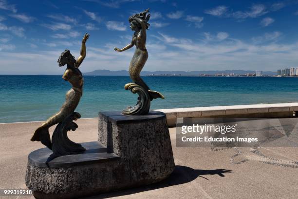 Triton with broken arm and Mermaid bronze statues on the Malecon of Puerto Vallarta Mexico.