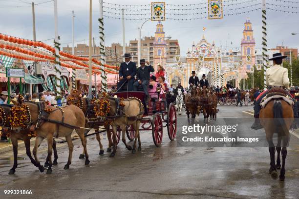 Horse and mule drawn carriages and riders on Antonio Bienvenida street with Main Gate 2015 Seville April Fair.