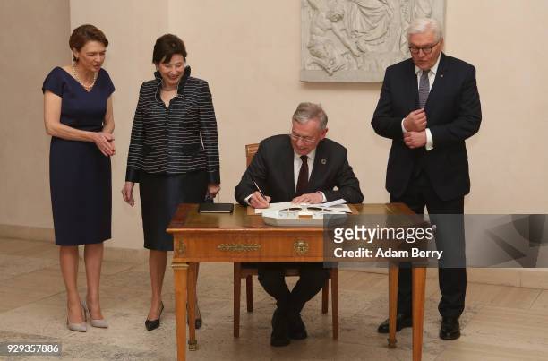 Former German President Horst Koehler signs a guest book as he attends a dinner in his honor during his 75th birthday, next to Koehler's wife Eva...