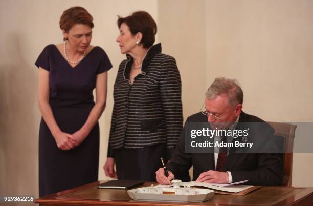 Former German President Horst Koehler signs a guest book as his wife Eva Luise Koehler and German President Frank-Walter Steinmeier's wife Elke...