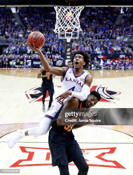 Devonte' Graham of the Kansas Jayhawks drives toward the basket as Yankuba Sima of the Oklahoma State Cowboys defends during the Big 12 Basketball...