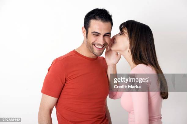 Young Woman Talking Into Young Man's Ear.