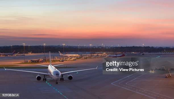 Airfield with plane arriving at sunset. Manchester Airport, Manchester, United Kingdom. Architect: n/a, 2015.