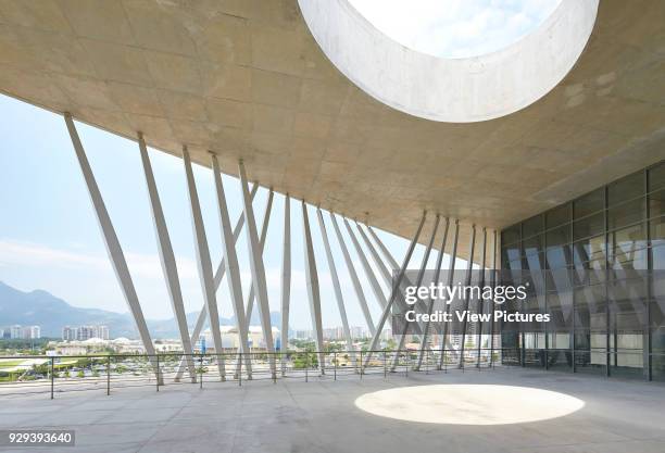 Canopied public plaza and terrace with circular void and city view. La Cidade das Artes, Barra da Tijuca, Brazil. Architect: Christian de...