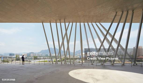 View from canopied public plaza towards city and mountains. La Cidade das Artes, Barra da Tijuca, Brazil. Architect: Christian de Portzamparc, 2014.
