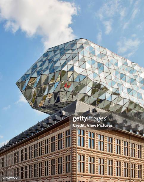 Corner view of old fire station and floating glazed volume. Port House, Antwerp, Belgium. Architect: Zaha Hadid Architects, 2016.