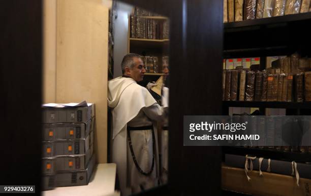 Father Najeeb Michaeel, a friar of the Dominican Order, stands by old Christian books at the Oriental Manuscript Digitisation Centre in Arbil, the...