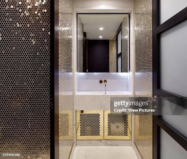 Mirror and wash basin detail in gold tiled bathroom. 54 Brooks Mews, London, United Kingdom. Architect: Stiff + Trevillion Architects, 2016.