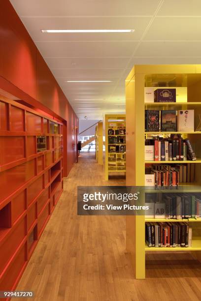 Yellow bookshelves with red wall on left on first floor.