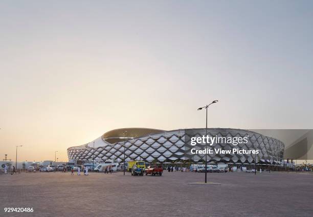 Hazza Bin Zayed Stadium, Al Ain, Al Ain, United Arab Emirates. Architect: Pattern Design, 2014. Distant contextual view of stadium with car park at...