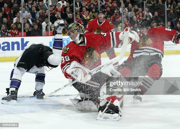 Goalie Cristobal Huet of the Chicago Blackhawks turns towards the puck as Tomas Kopecky of the Chicago Blackhawks and a player from the Los Angeles...