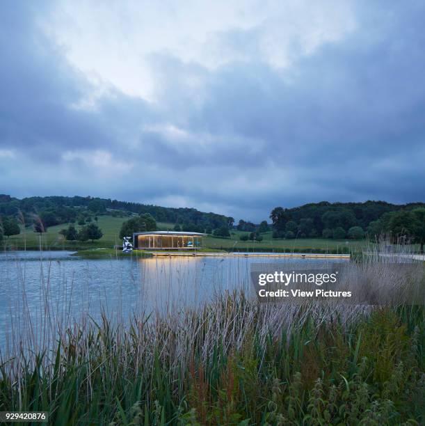 Lake with island pavilion at dusk. Island Pavilion and Footbridge, High Wycombe, United Kingdom. Architect: Snell Associates, 2014.