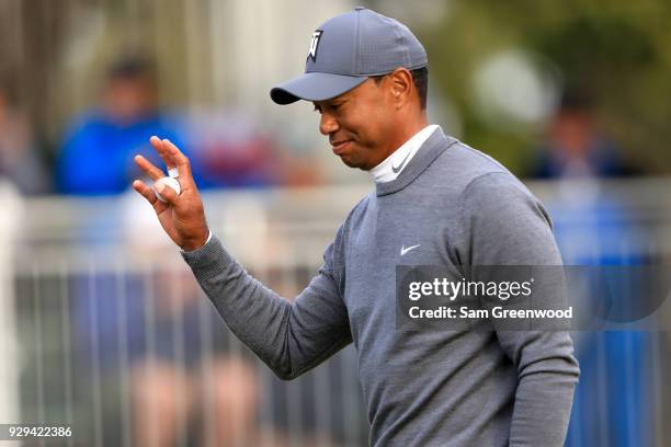 Tiger Woods waves to the crowd after a birde putt on the 17th green during the first round of the Valspar Championship at Innisbrook Resort...