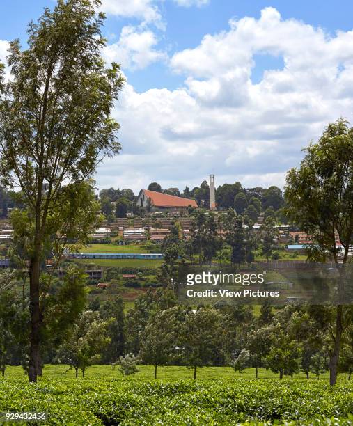Distant view over tea plantations and Local housing. Sacred Heart Cathedral Of The Catholic Diocese Of Kericho, Kericho, Kenya. Architect: John...