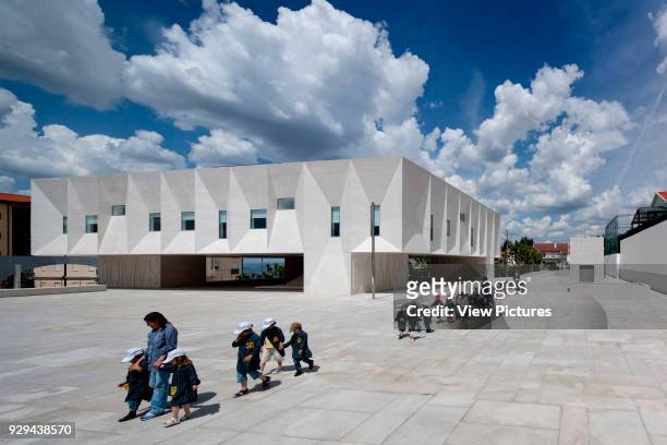 Corner elevation of court building on public square with children passing by. Palacio da Justicia de Gouveia, Gouveia, Portugal. Architect: Barbosa &...