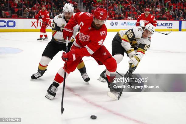 Henrik Zetterberg of the Detroit Red Wings tries to control the puck between Erik Haula and Tomas Tatar of the Vegas Golden Knights during the first...