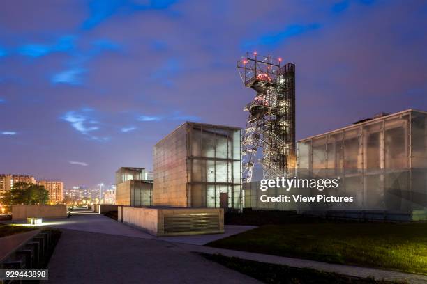 Museum site at night with illuminated city beyond. Silesian Museum, Katowice, Poland. Architect: Riegler Riewe Architekten, 2014.