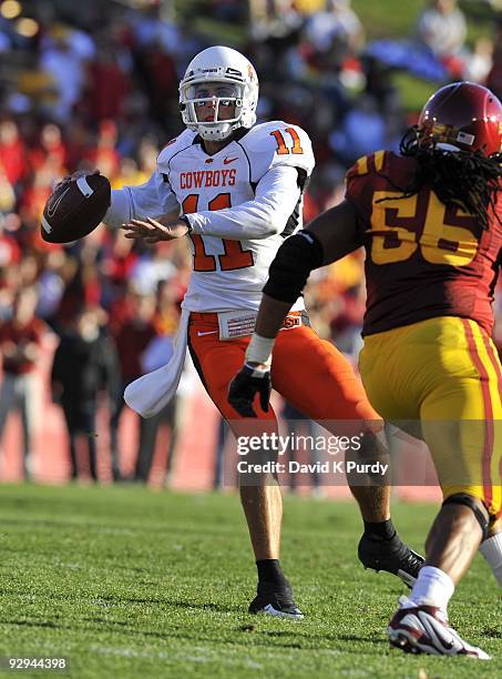 Quarterback Zac Robinson of the Oklahoma State Cowboys throws under pressure from defensive end Christopher Lyle of the Iowa State Cyclones in the...