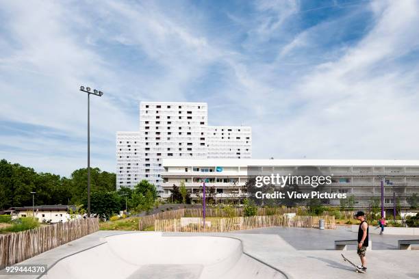 Long distance view from nearby skateboard park showing housing context. Urban Renovation Genicart Lormont in Bordeaux, Bordeaux, France. Architect:...