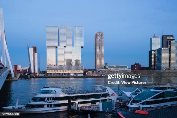 Evening view of front elevation as seen across the river Maas. De Rotterdam Vertical City, Rotterdam, Netherlands. Architect: OMA Rem Koolhaas, 2013.