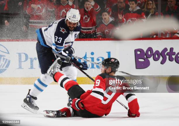 Dustin Byfuglien of the Winnipeg Jets hits Taylor Hall of the New Jersey Devils during the second period at the Prudential Center on March 8, 2018 in...