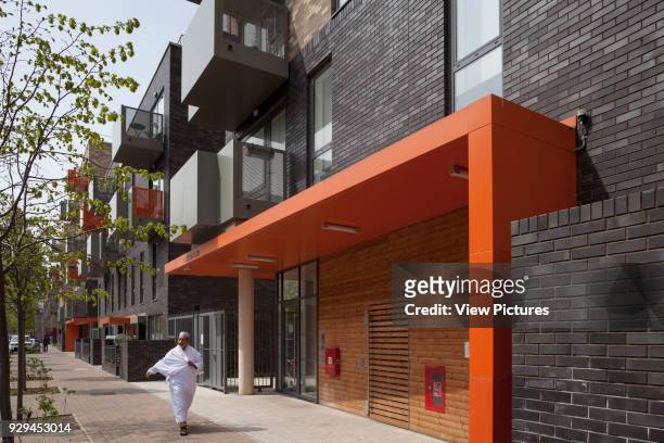 Exteriors, orange portico with figure in white. Ocean Estate, London, United Kingdom. Architect: Levitt Bernstein, 2015.