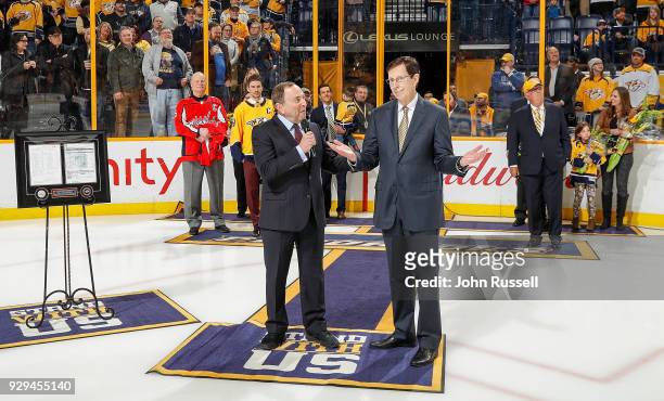 Commissioner Gary Bettman congratulates Nashville Predators GM David Poile on his record breaking 1320 career wins as a GM in the NHL prior to a game...