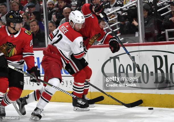 Brett Pesce of the Carolina Hurricanes works to get the puck against Brandon Saad and Jonathan Toews of the Chicago Blackhawks in the first period at...