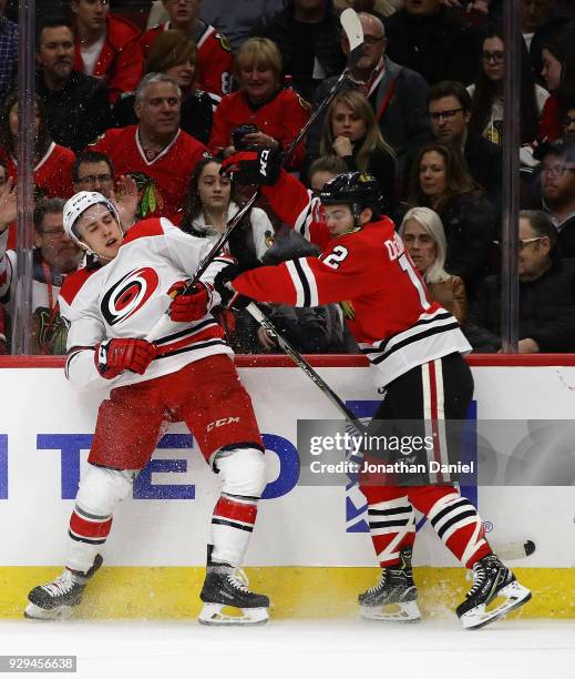 Alex DeBrincat of the Chicago Blackhawks hits Teuvo Teravainen of the Carolina Hurricanes at the United Center on March 8, 2018 in Chicago, Illinois.